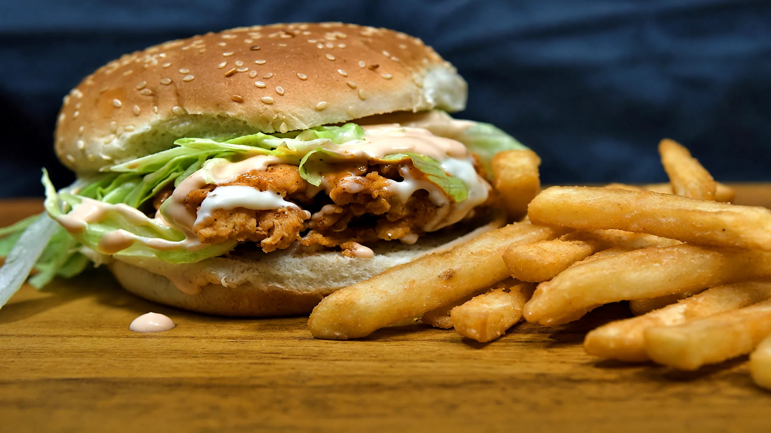 Chicken Zinger burger with crispy chicken, lettuce and sauce, beside fries